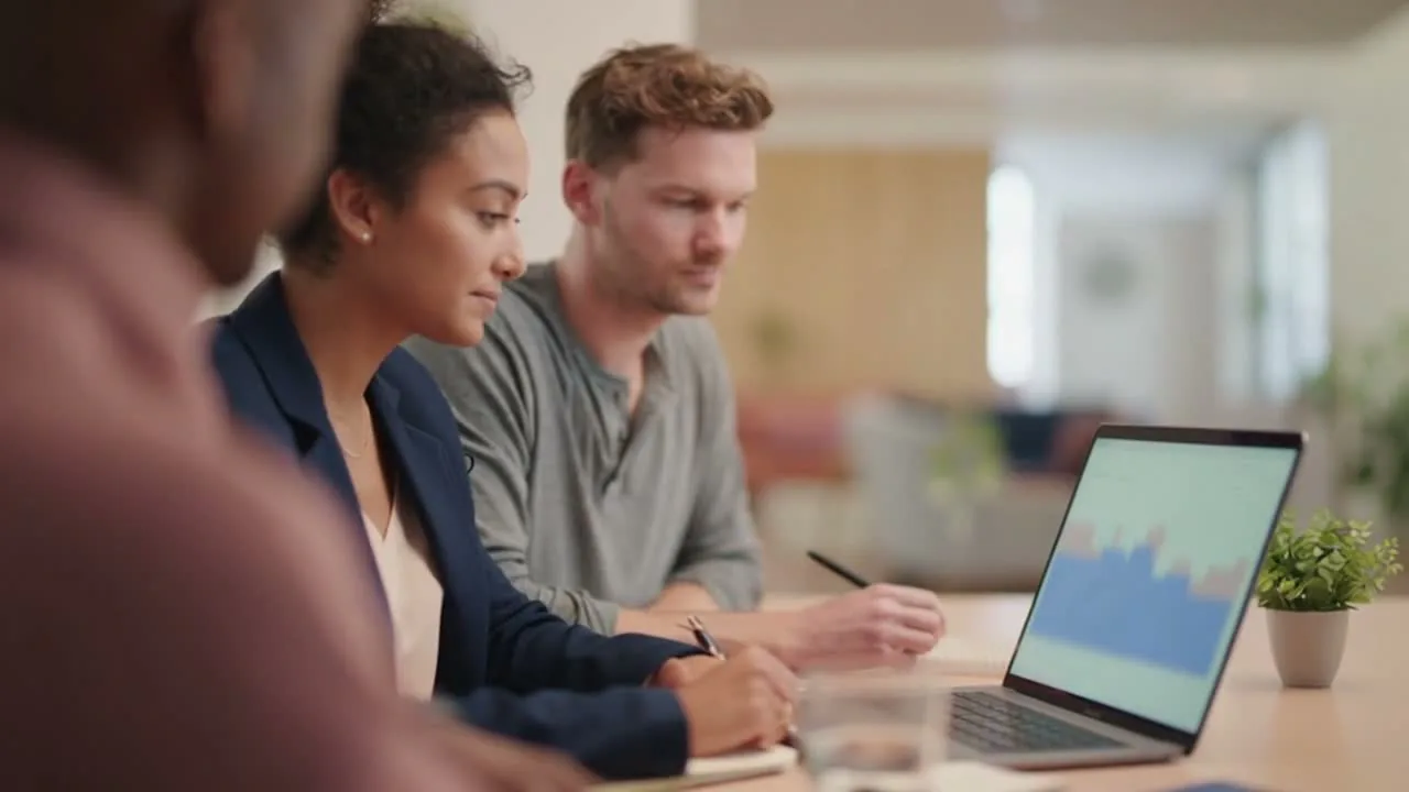 A cross-functional office team reviews digital work around a conference table.